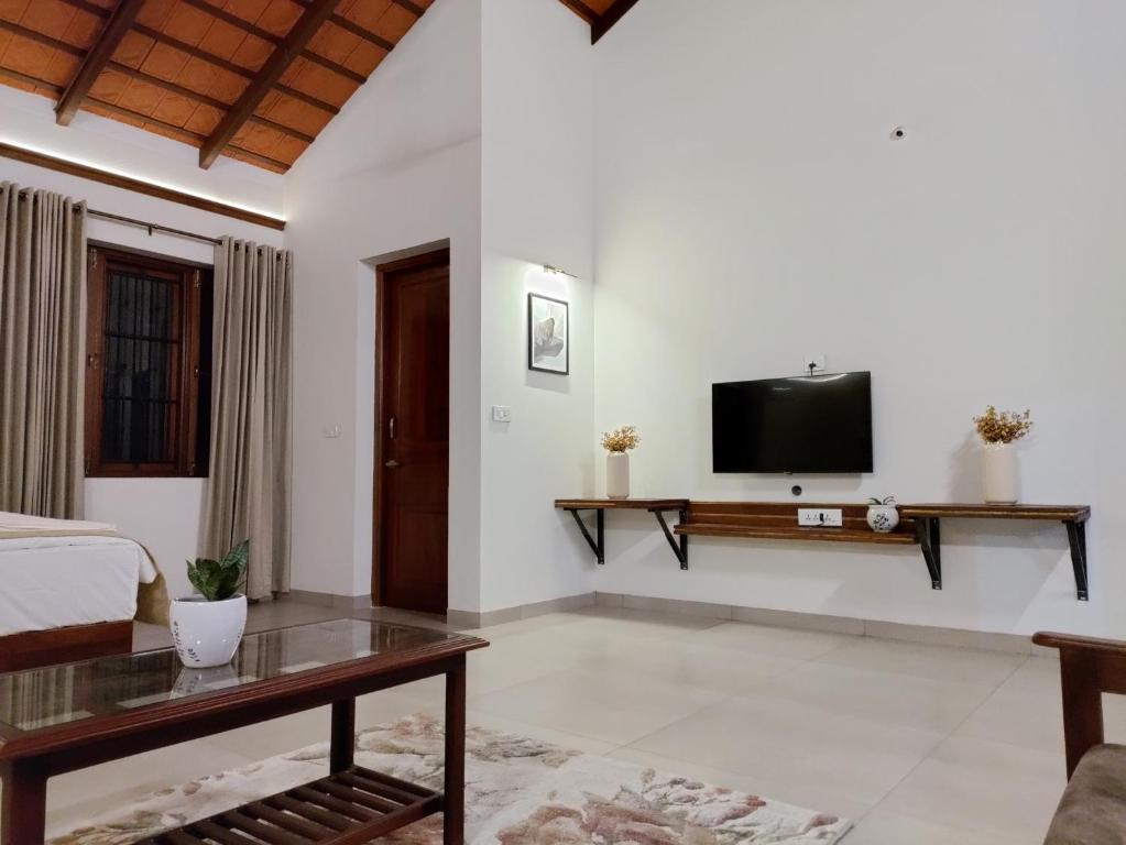 a bedroom with a bed and a tv on a wall at The Cana's Coorg in Ammatti