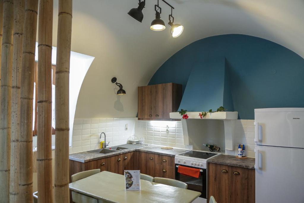 cocina con nevera blanca y armarios de madera en Stylianos House 1 en Leonídion