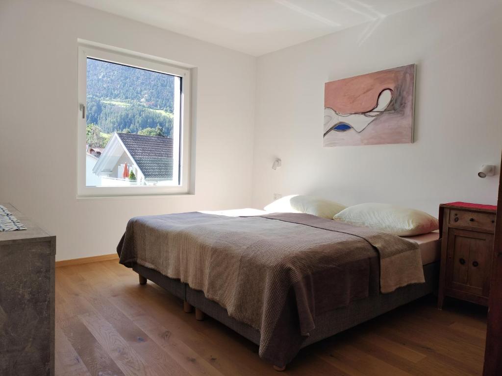 a white bedroom with a bed and a window at Haus am Brunnen in Prato allo Stelvio