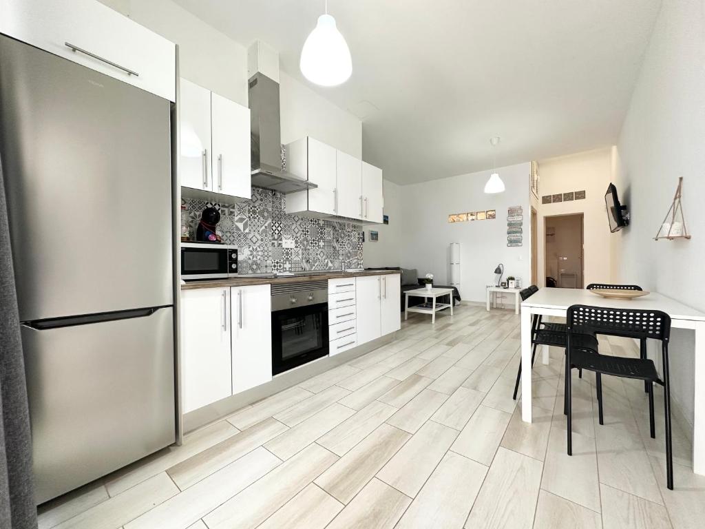 una cucina con armadi bianchi, tavolo e frigorifero di Cotillo Luna by Lovely Property a Cotillo