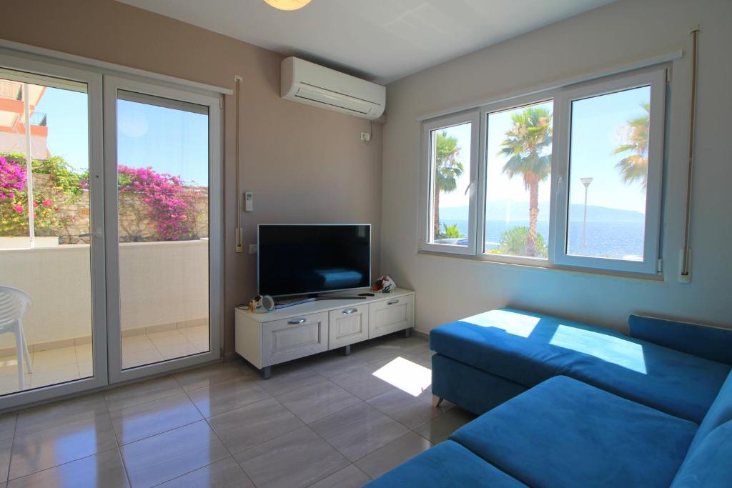 a living room with a blue couch and a flat screen tv at Beachfront Sion Sarande Apartment 2 in Sarandë