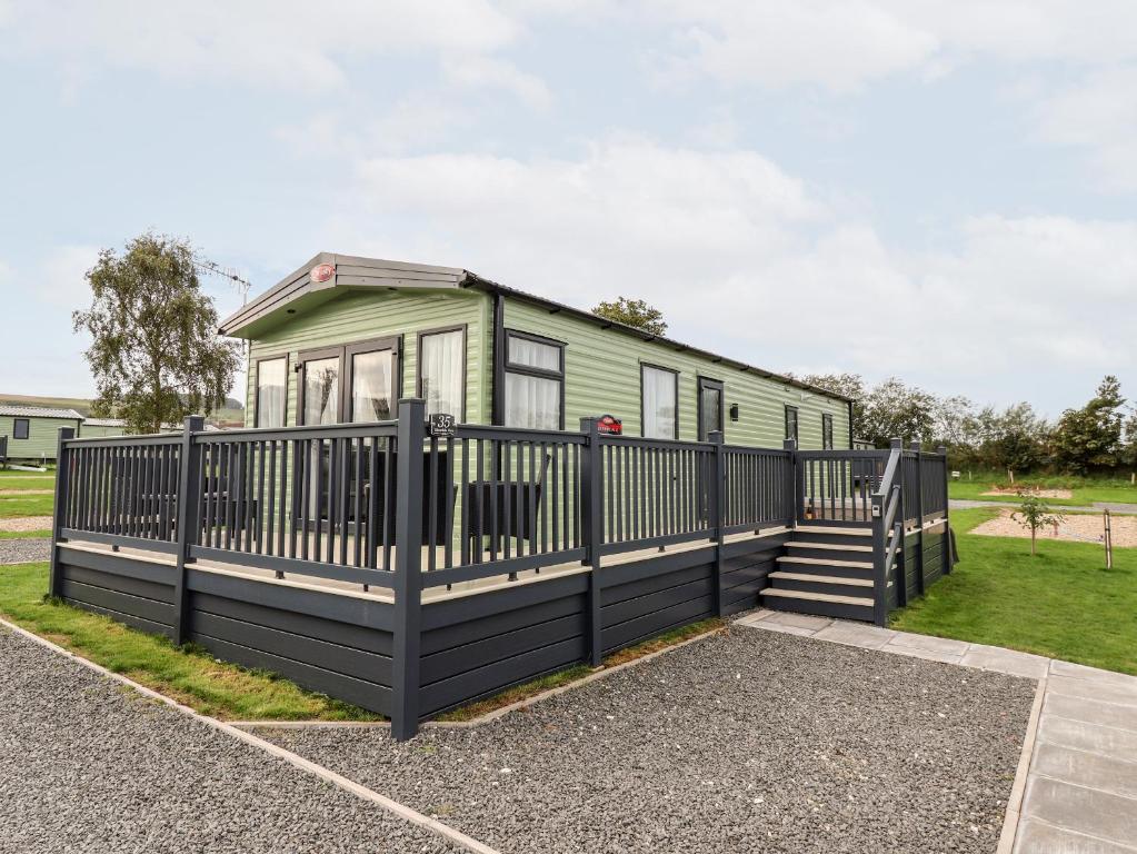 a green tiny house with a black fence at Silverdale View in Ganton