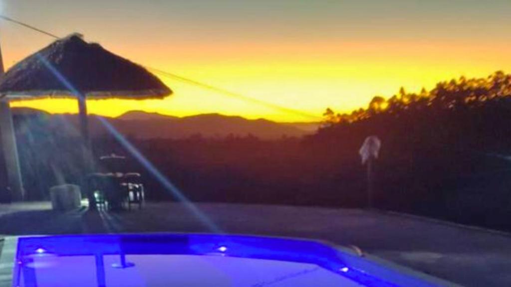 een hot tub met een zonsondergang op de achtergrond bij Lindo chalé no alto da colina, vista paradisíaca do por do sol, proximo a praia e cachoeiras in Pariqueraçu