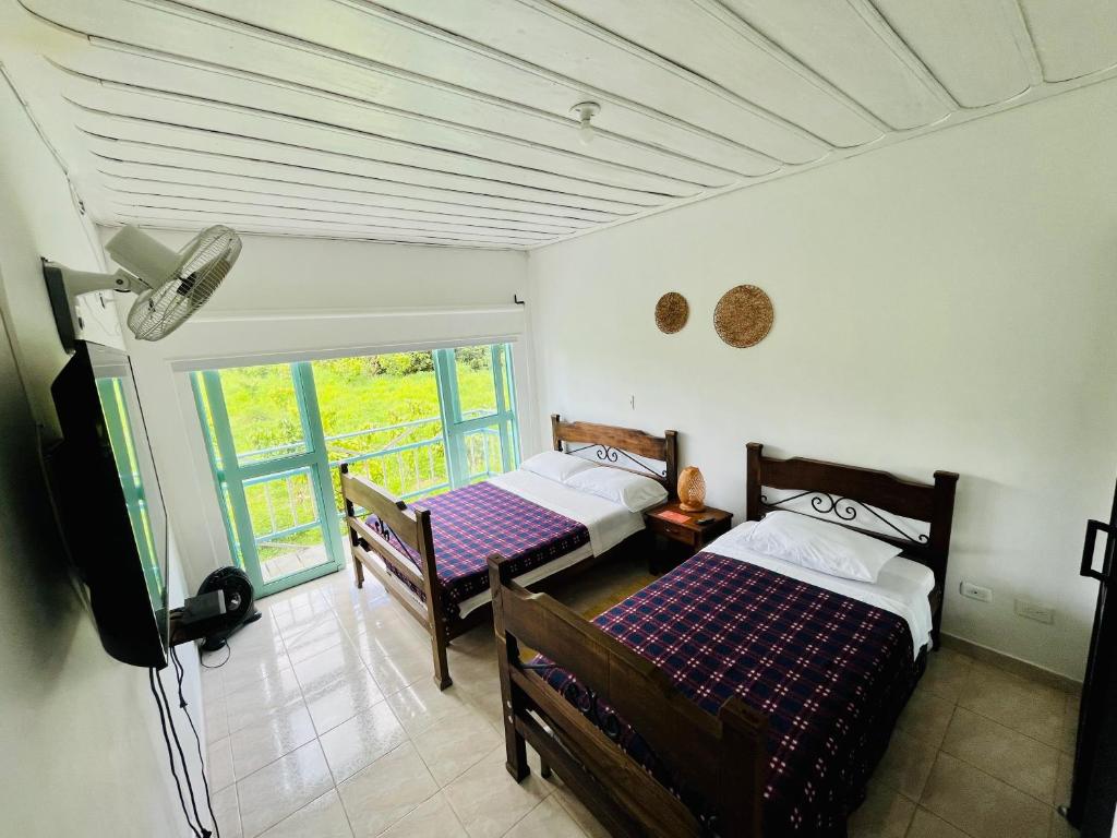 1 dormitorio con 2 camas y ventana en La Posada Circa, en Montenegro