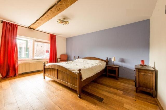 a bedroom with a bed and a window with red curtains at Farm Stay Luythoeve in Meeuwen