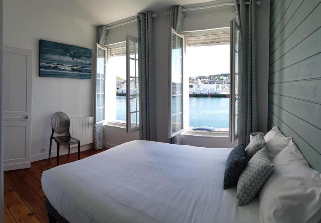 um quarto com uma grande cama branca e janelas em Le Hublot charmante maison au calme Fécamp vue sur le port em Fécamp
