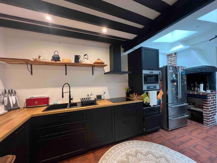 a kitchen with black cabinets and a refrigerator at Ravissante maison de pêcheurs Trouville proche centre et gare in Trouville-sur-Mer
