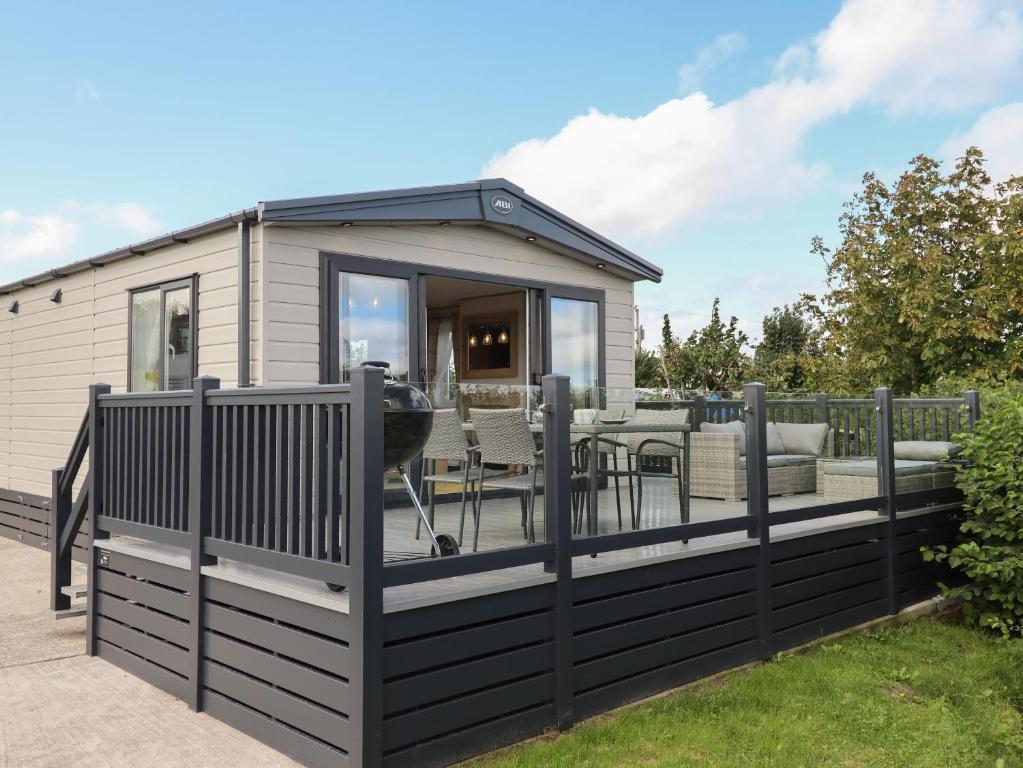 a tiny house with a black fence and a deck at Hazel Lodge in Newton Abbot