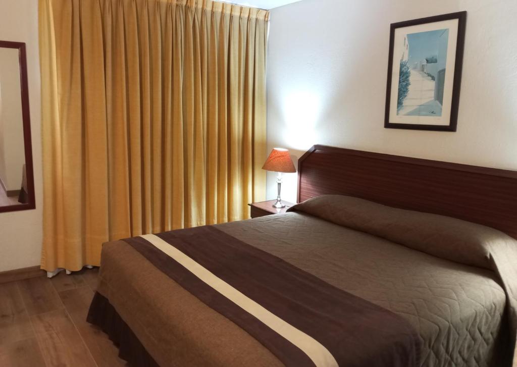 a bedroom with a bed and a window with yellow curtains at Hotel Alcala del Rio in Santiago