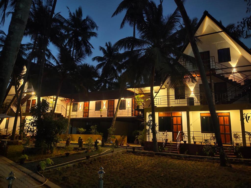 a white house with palm trees in front of it at PV Cottages Serenity Beach in Puducherry
