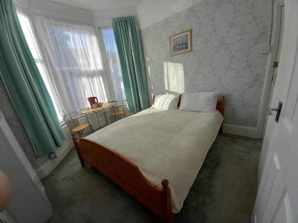 1 dormitorio con 1 cama grande y cortinas verdes en Mari London room for holiday, en Ilford