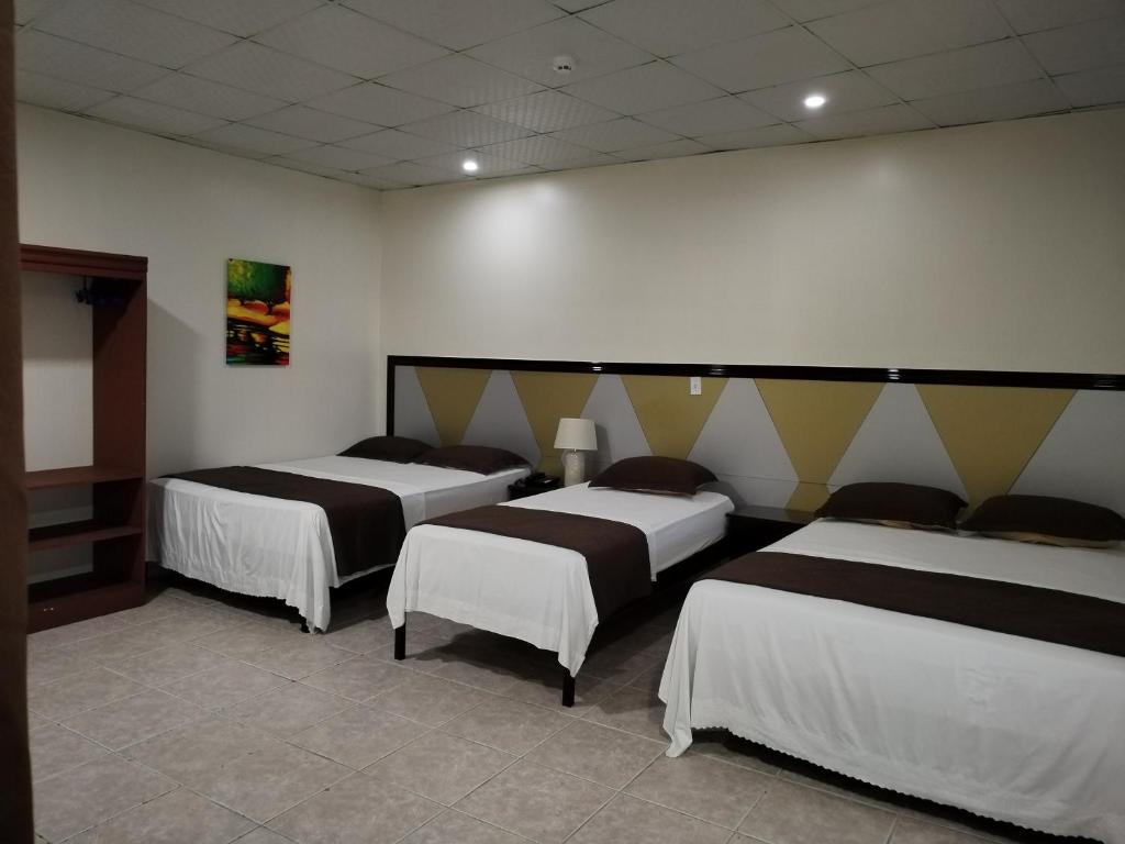 Habitación con 4 camas en una habitación en Hotel America - La Chorrera, en La Chorrera