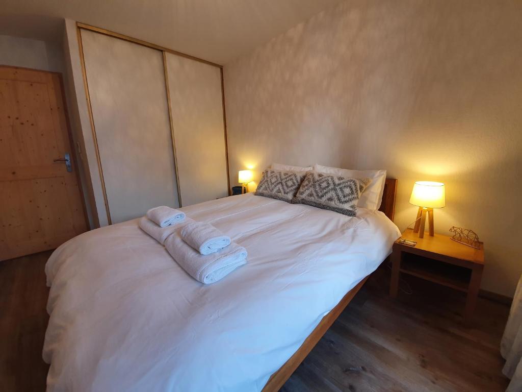 ein Schlafzimmer mit einem weißen Bett mit zwei Handtüchern darauf in der Unterkunft Le Clos B11 - 3 bedroom apartment 5 minutes walk to the square in Samoëns