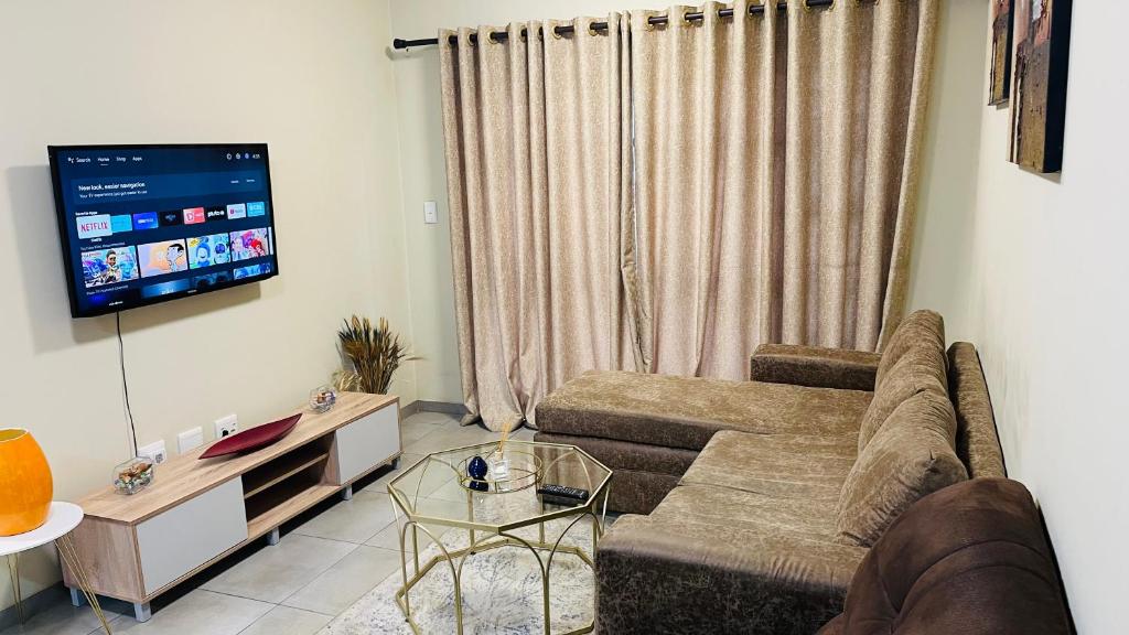 uma sala de estar com um sofá e uma televisão de ecrã plano em Mall Of Africa Spot3 By Damo em Midrand