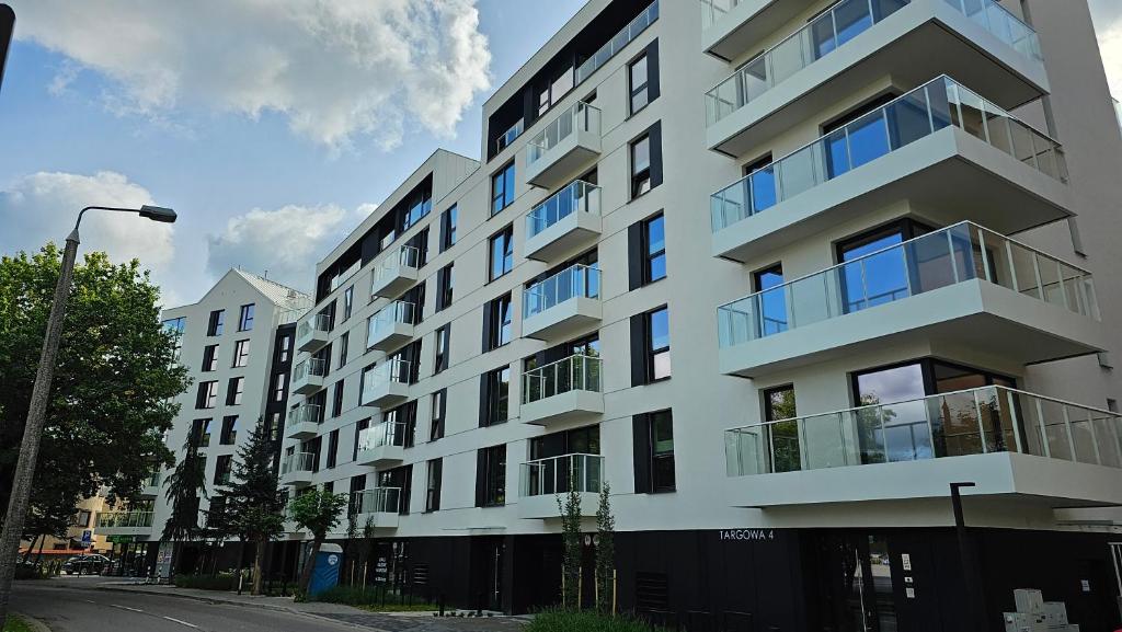 a white apartment building with balconies on a street at Apartament Mono Ełk CENTRUM in Ełk