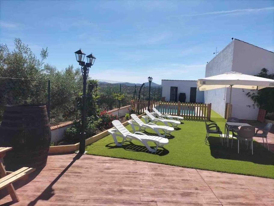 a row of lounge chairs and an umbrella on a lawn at Casa con encanto, gran capacidad alojamiento-24 personas in Doña Rama