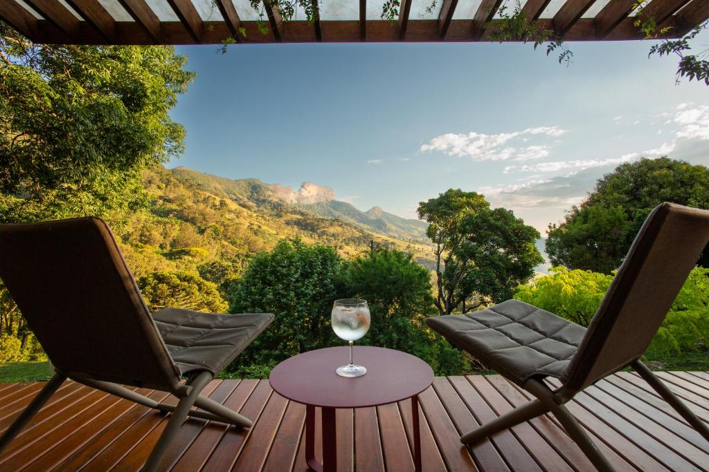 two chairs and a glass of wine on a deck at Chalé Leopoldo-Nas Nuvens in São Bento do Sapucaí