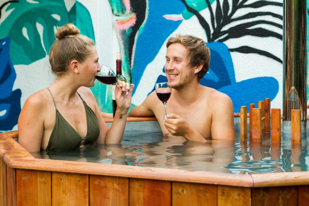 Hostal Aldea Colchagua Experience في سانتا كروز: رجل وامرأة في حوض استحمام ساخن يشربان النبيذ