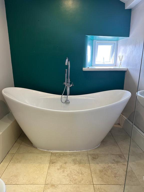 uma banheira branca numa casa de banho com uma parede verde em Sugar Plum Cottage em Conisbrough