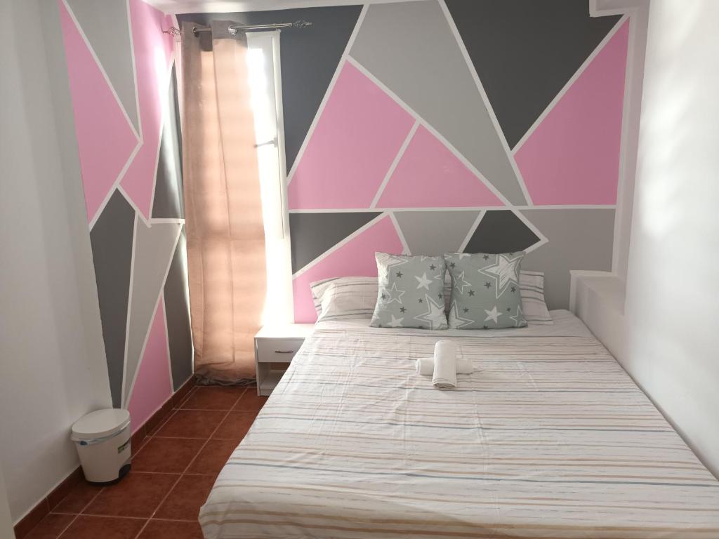 een slaapkamer met een bed met een roze en grijze muur bij Habitación D&D Habitación en piso particular in Valencia