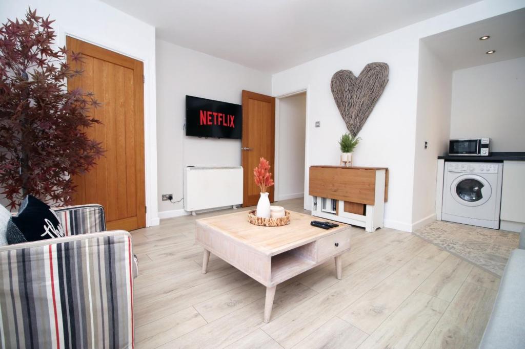 a living room with a table and a heart on the wall at Central Mumbles Apartment, Properties By O & G, Incredible Location, Sleeps 4! in The Mumbles
