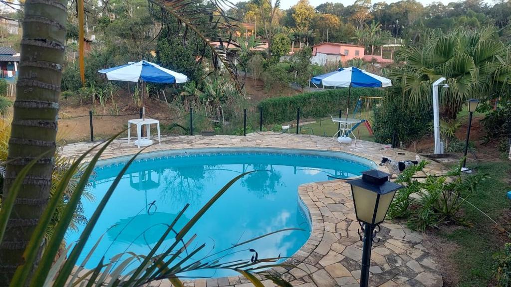 a swimming pool in a yard with umbrellas at Chácara Recanto do Sol in Mogi das Cruzes