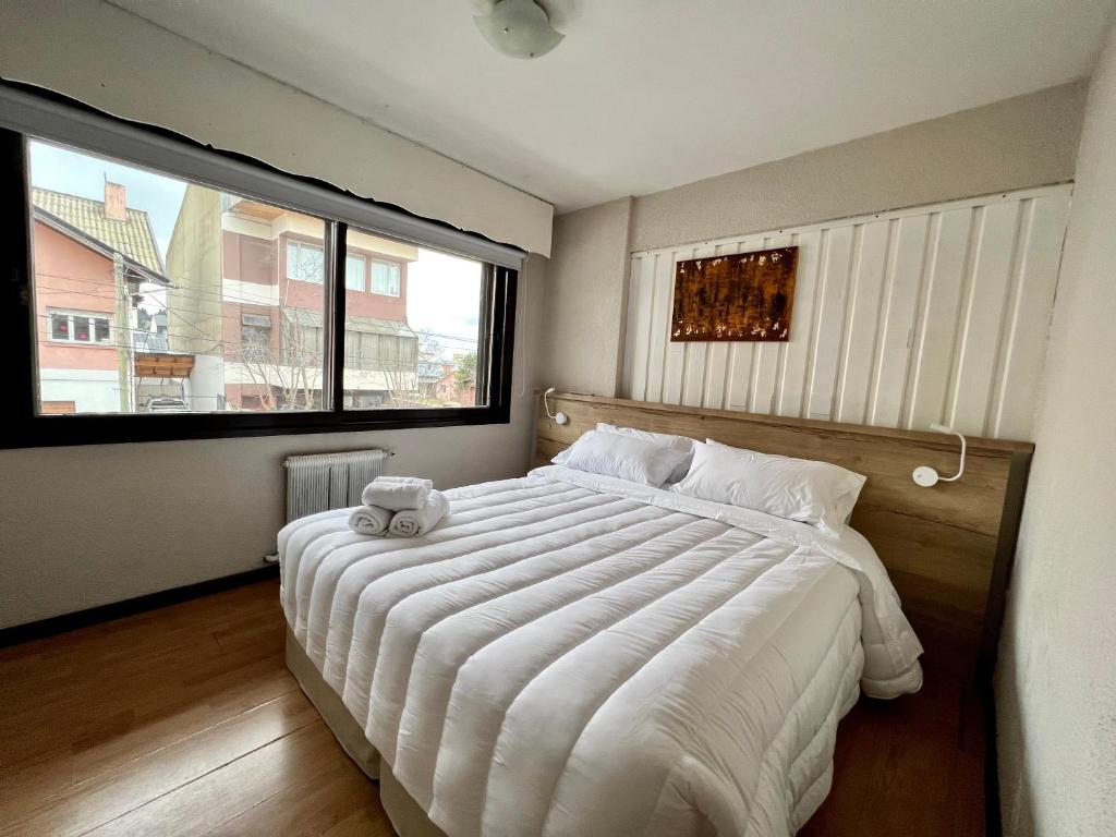 - une chambre avec un grand lit et une grande fenêtre dans l'établissement El Residencial Bariloche, à San Carlos de Bariloche