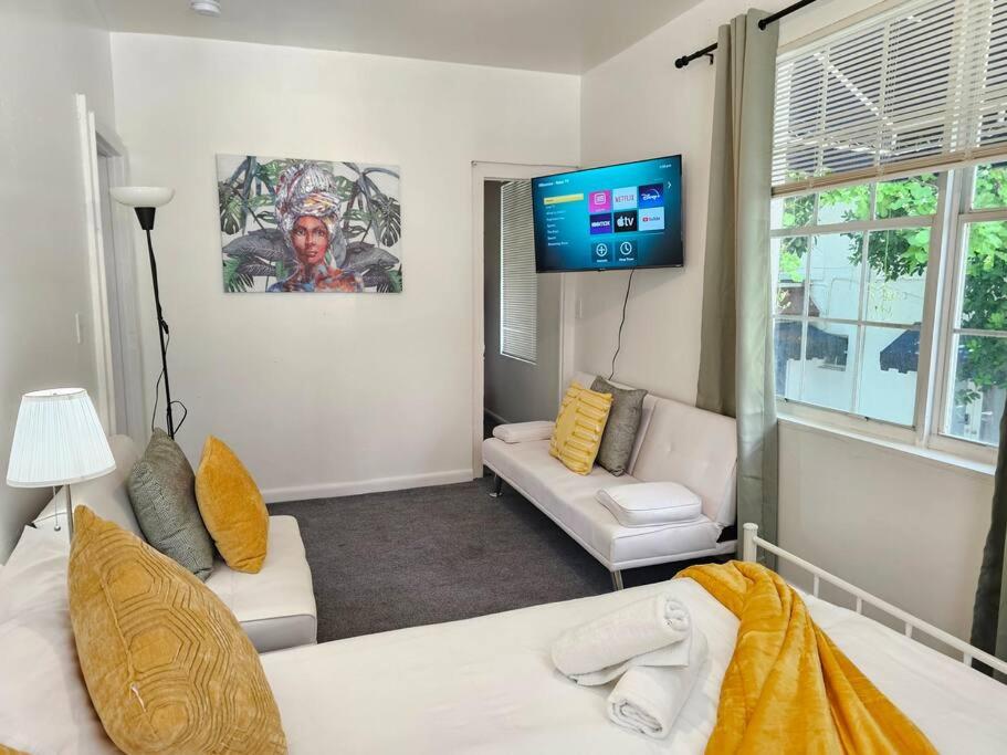 ein Wohnzimmer mit einem Sofa und einem Flachbild-TV in der Unterkunft Bungalow King n Queen Bed 5m Wynwood Kitchen in Miami