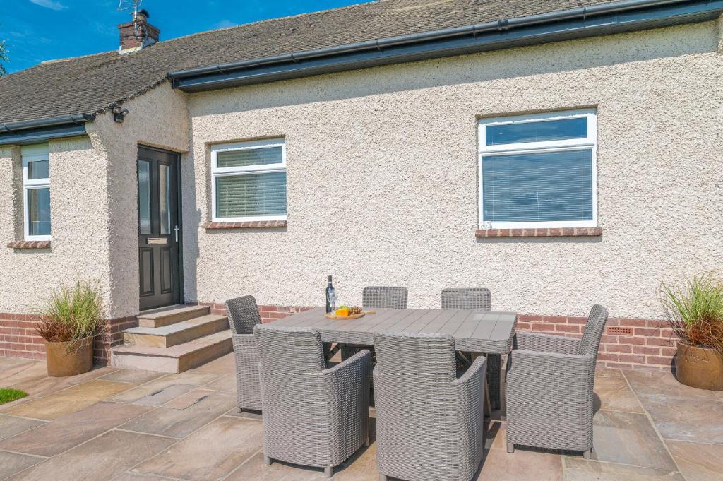 a patio with a table and chairs in front of a house at Colt Park Cottage in Ulverston