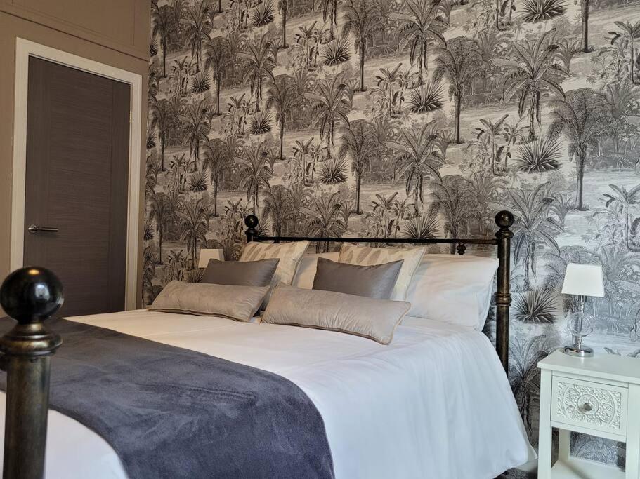 a bedroom with a large white bed with a wallpaper at Cameronian Apartment in Stirling