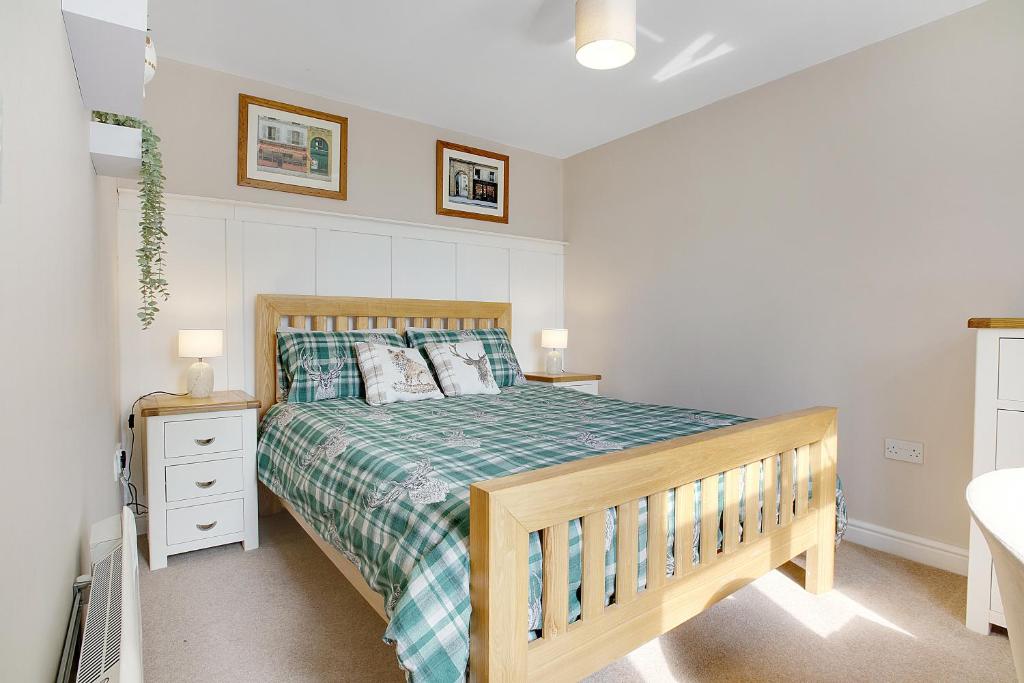 a bedroom with a wooden bed with a green bedspread at Frenchgate Holiday Stay in Richmond