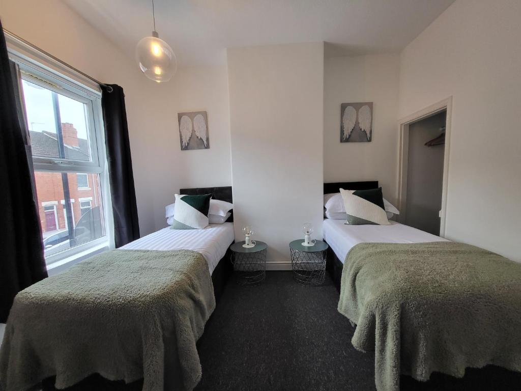 2 letti in una camera con finestra di Lovely Coventry Home - Suitable for Business, Contractors, Families, Relocators, mins walk to City Centre and University a Wyken