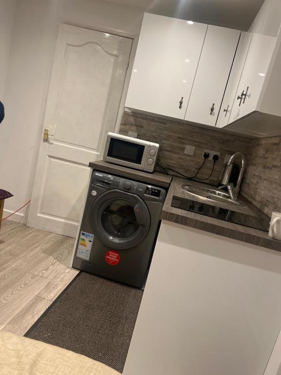 a kitchen with a washing machine and a microwave at Cozy small studio in Peterborough