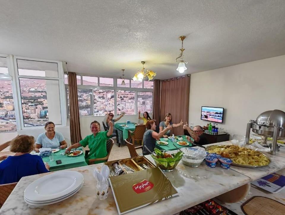 een groep mensen die rond een tafel zitten met eten bij iHome Petra in Wadi Musa