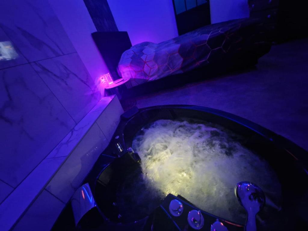Cette chambre sombre dispose d'une baignoire remplie d'eau bouillante. dans l'établissement Suite GOLD Mulhouse, à Mulhouse