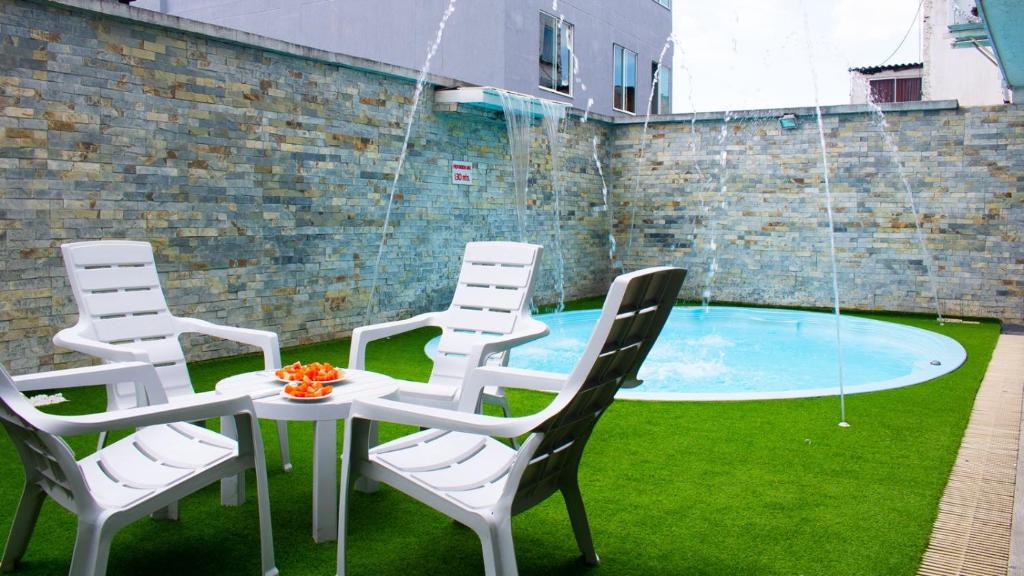 un grupo de sillas, una mesa y una piscina en HOTEL PLAZUELA REAL, en Bucaramanga