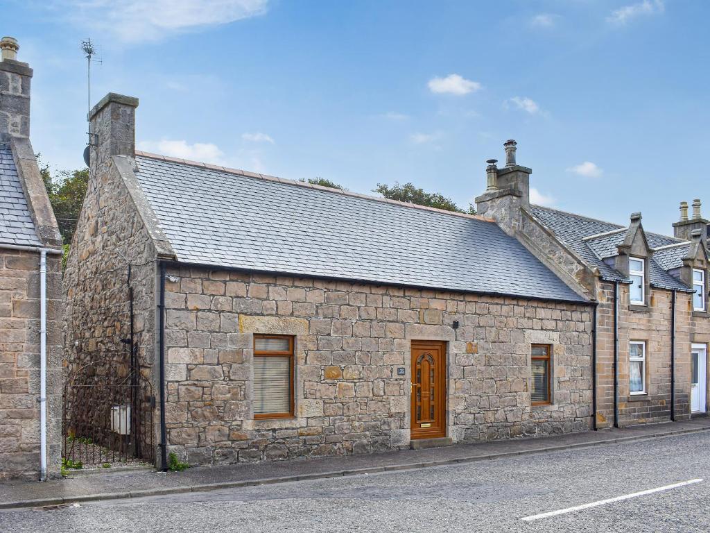 an old stone building on the side of a street at Braeside Cottage in Buckie
