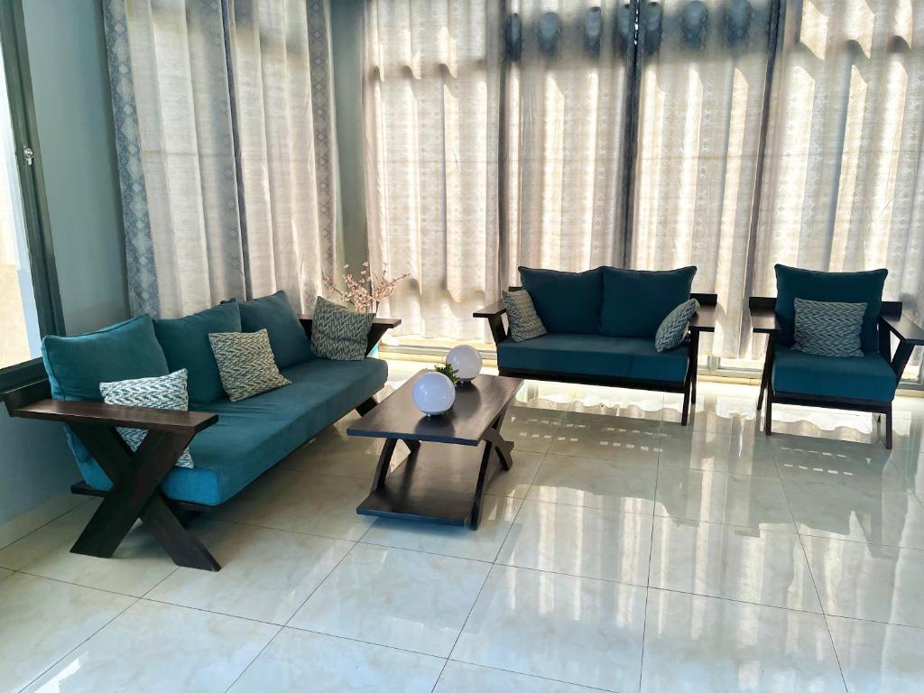 a living room with a blue couch and two chairs at Ruhuka House in Bujumbura