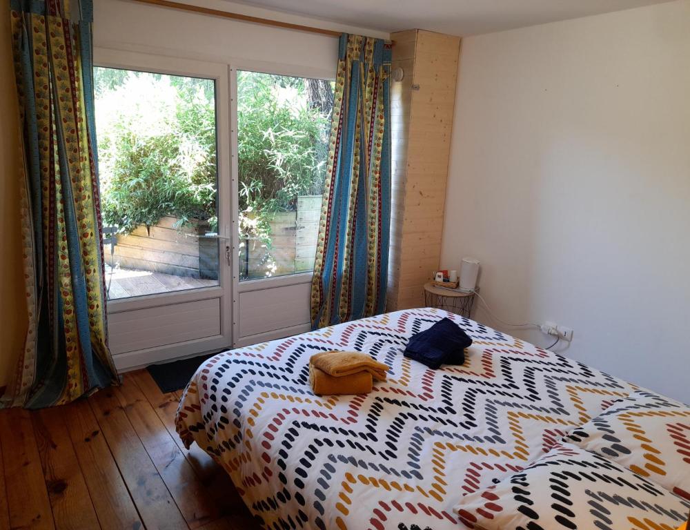 a bedroom with a bed and a large window at Le mas des Landes in Vielle-Saint-Girons