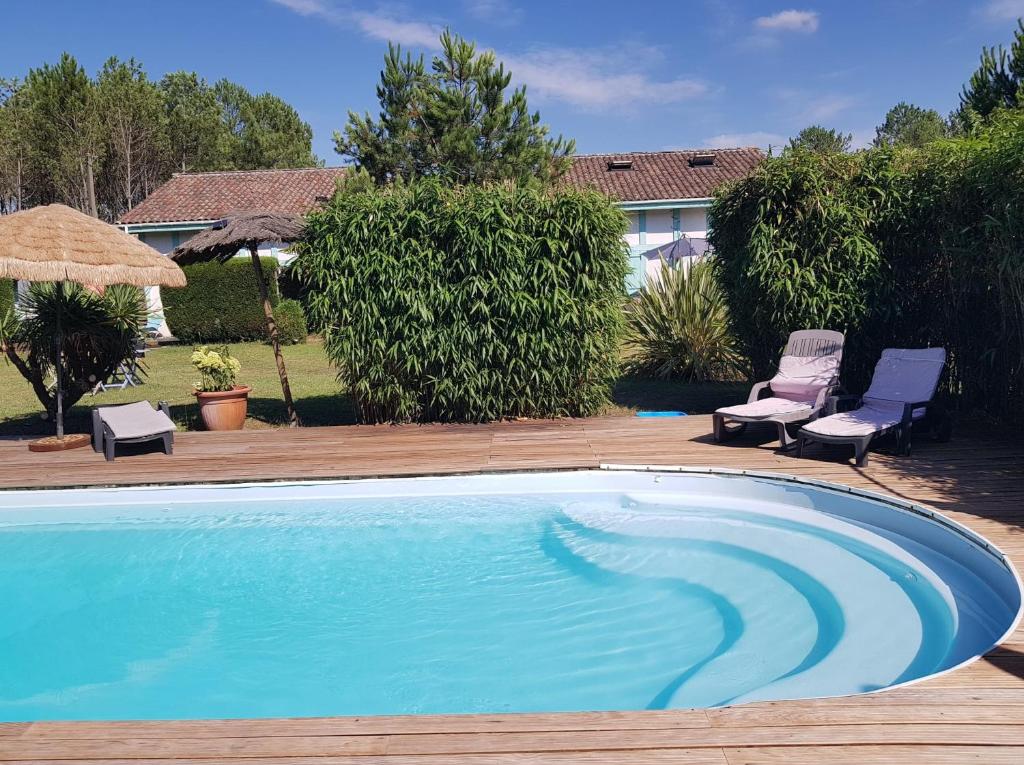 a swimming pool with two chairs and an umbrella at Le mas des Landes in Vielle-Saint-Girons