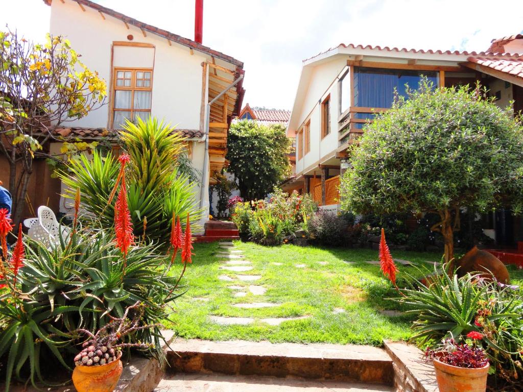 um jardim em frente a uma casa com flores vermelhas em Casona La Recoleta em Cusco