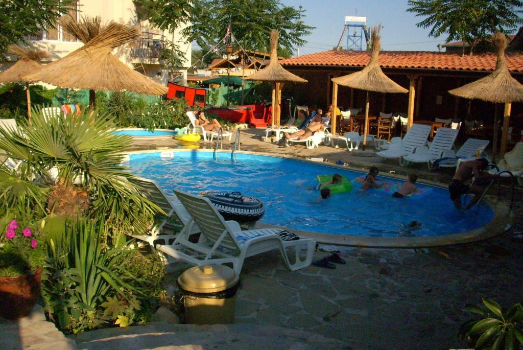 una piscina con sillas y gente en ella en Family hotel Tropicana en Ravda