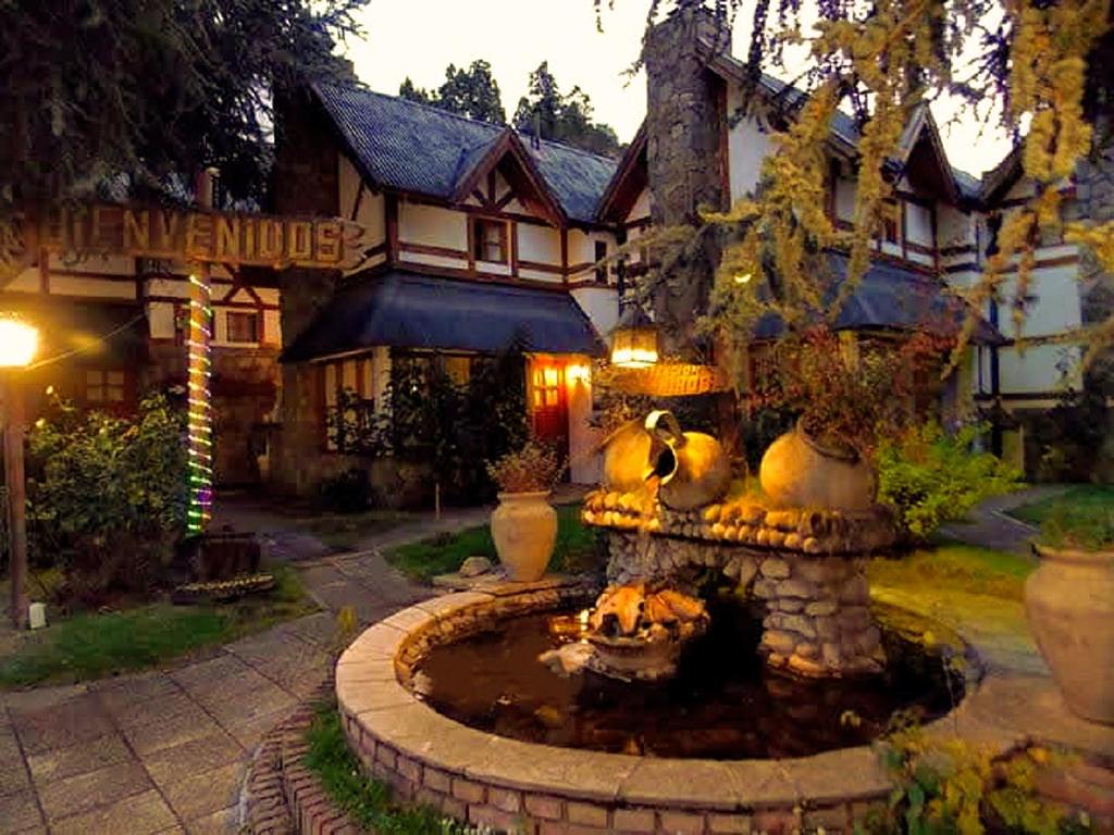 una grande casa con una fontana di fronte a un edificio di Cabañas Luz de Luna a San Martín de los Andes