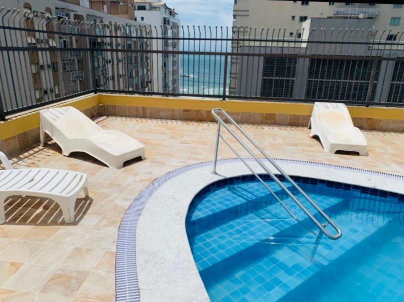 a swimming pool on a rooftop with two chairs and avisor at Boulevard Center in Guarujá