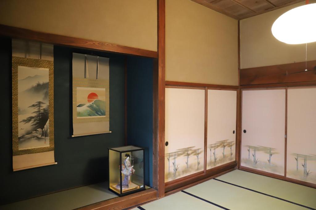 a room with glass doors and paintings on the wall at とんかつ&ヒーリングハウスえん in Shimmachi