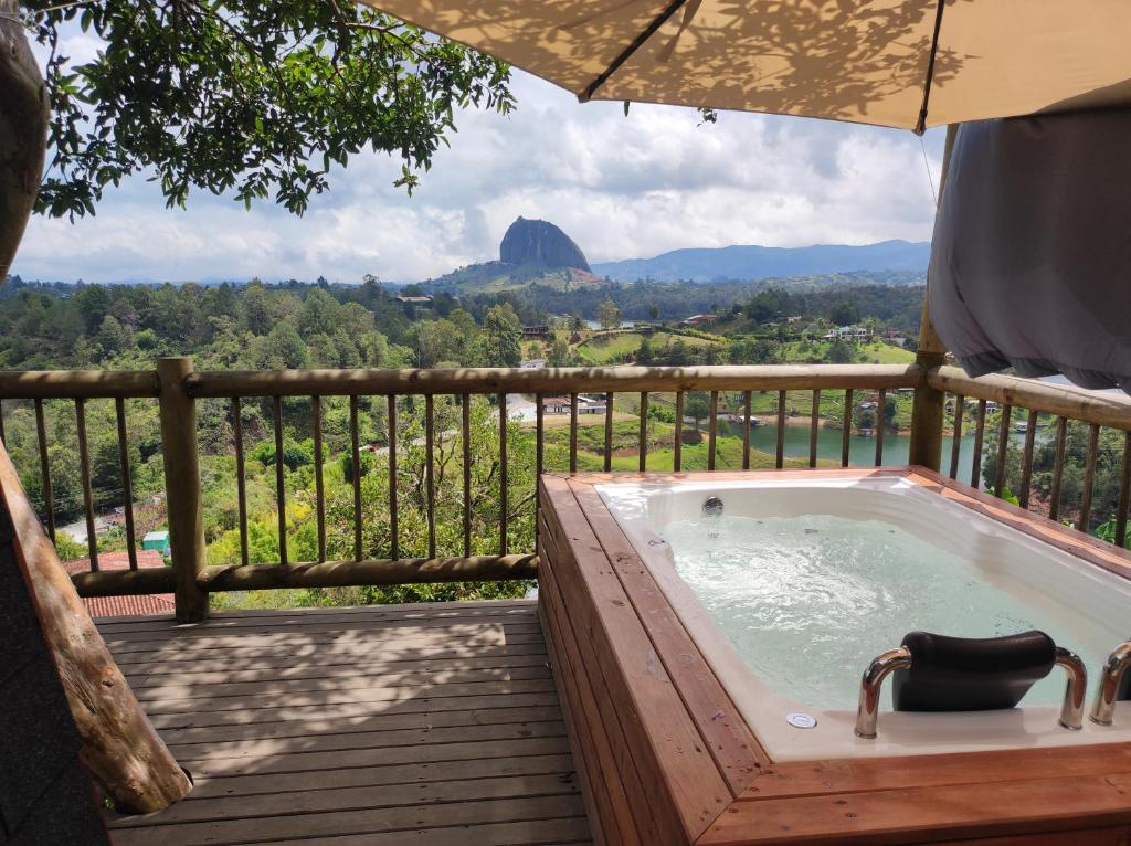 a jacuzzi tub on a deck with a view at Breeze Glamping -Guatape in El Peñol