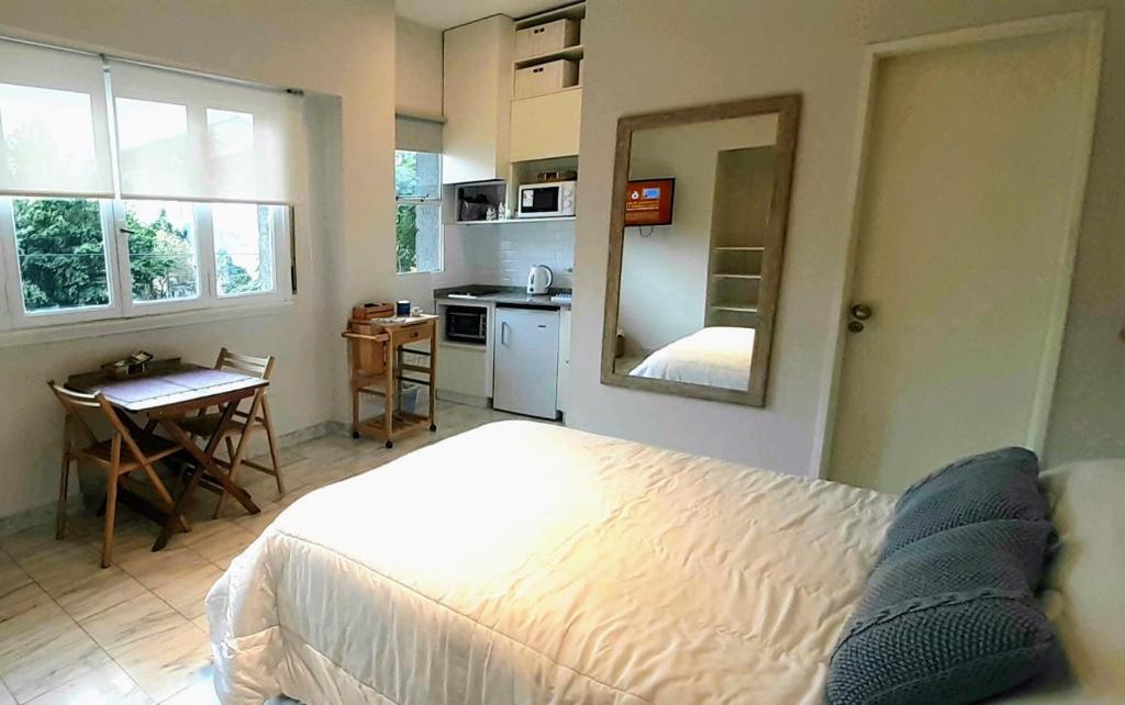 Apartamento centrico في بوينس آيرس: غرفة نوم بسرير ابيض ومطبخ