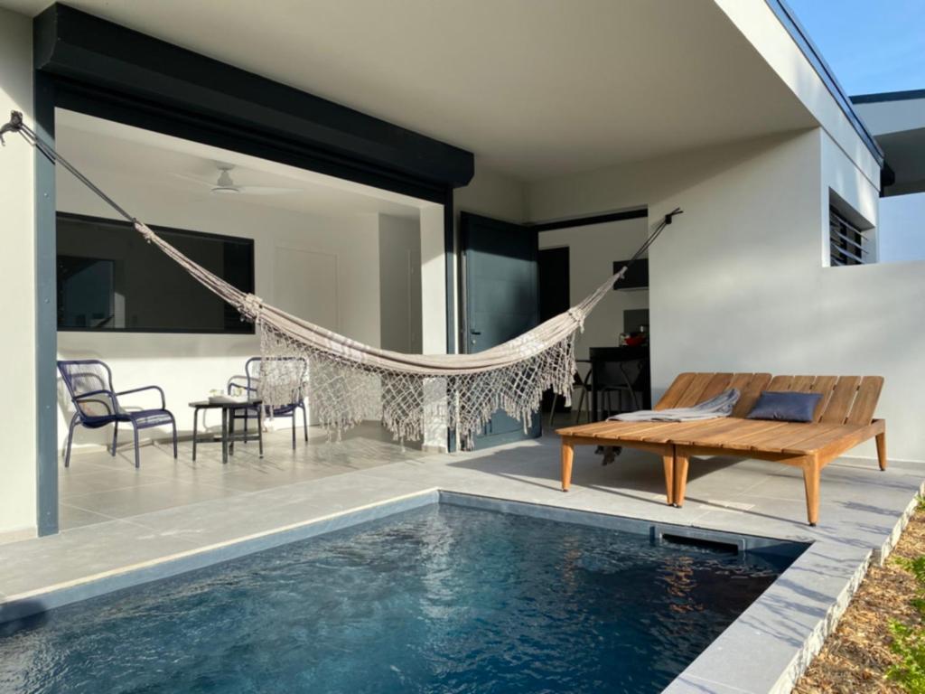 a villa with a swimming pool and a hammock at Hôtel Lune de Miel in Deshaies