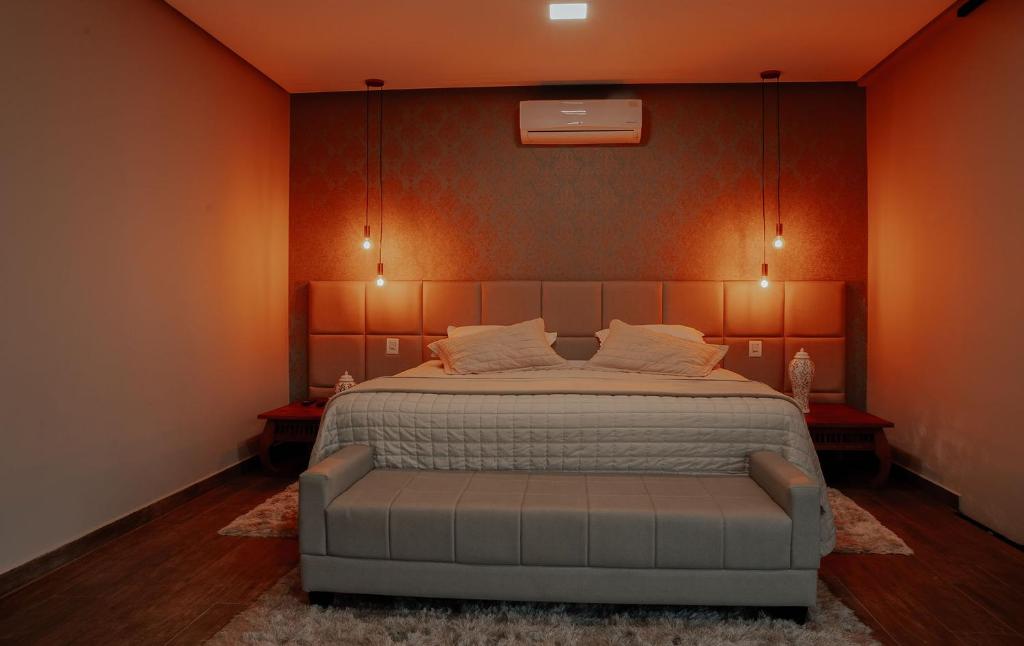 - une chambre avec un grand lit aux murs orange dans l'établissement Pousada Quinta dos Cabeças, à Capitólio