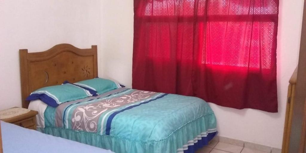 1 dormitorio con 1 cama y una ventana con cortinas rojas en ELHUASTECO en Cuernavaca